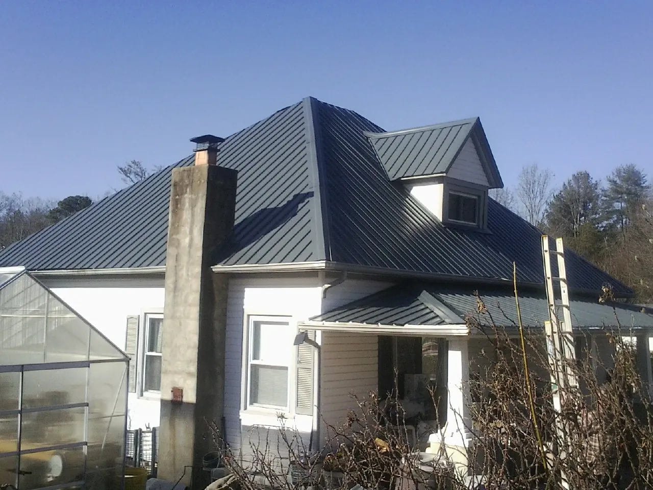 Dark blue standing seam metal roof on a white farmhouse with dormer — Slate & Tile Roof Repair by Roofing Brothers in Simi Valley